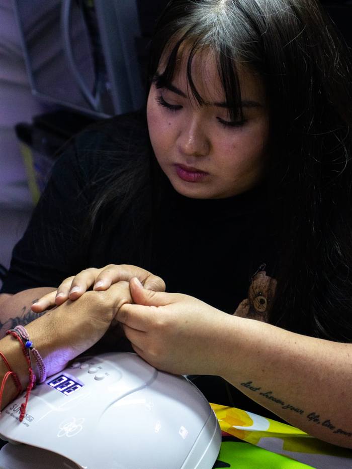 Especialista de ROOR atendiendo a un cliente junto a la lámpara de uñas