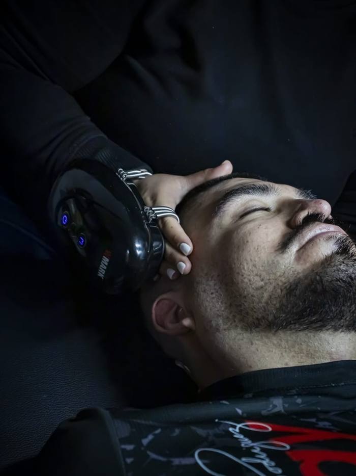 Masaje facial con equipo a un cliente recostado